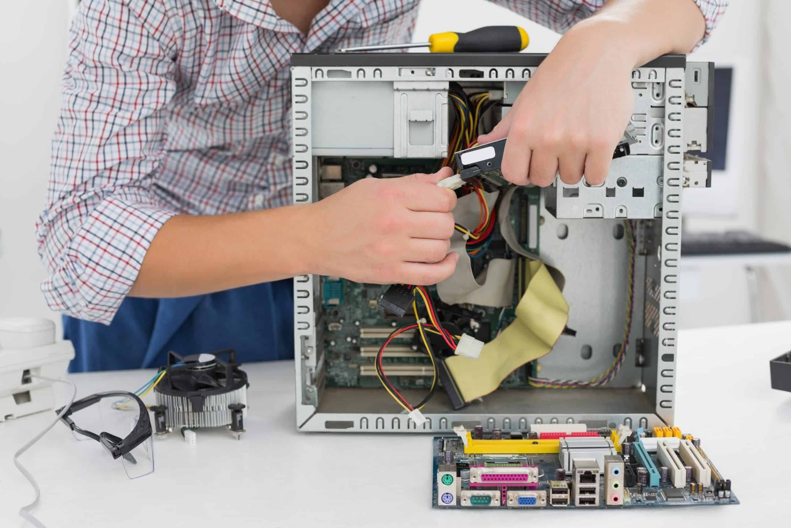 Young technician working on broken computer in his office